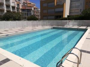 a swimming pool with blue water in a building at Studio - résidence avec piscine in Cap d'Agde
