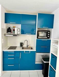 a blue kitchen with a sink and a microwave at Studio - résidence avec piscine in Cap d'Agde
