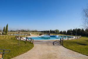 a swimming pool in a park on a sunny day at Hospedium Hotel Cortijo Santa Cruz in Villanueva de la Serena