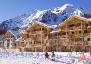 2 personnes debout dans la neige devant un lodge de ski dans l'établissement Vacances au coeur des Orres 1800, aux Orres