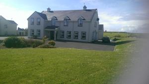 ein großes weißes Haus mit einem Rasenplatz in der Unterkunft Suantrai Accommodation in Doolin