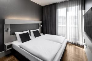 a large white bed in a room with a window at Hotel AMANO Rooms & Apartments in Berlin