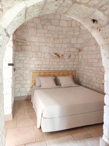 a bedroom with a bed in a stone wall at Il Giardino degli Ulivi in Castellana Grotte