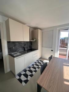 瓦莱克罗夏Camping Vallecrosia的厨房配有白色橱柜和一张桌子,铺有 ⁇ 格地板