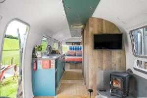 an interior view of a caravan with a kitchen and a stove at Airstream, Devon Hideaways in Kenton