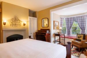 1 dormitorio con cama blanca y chimenea en Mira Monte Inn & Suites, en Bar Harbor