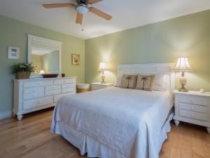 a bedroom with a white bed with two dressers and a fan at 1248 Creekwatch Villa in Seabrook Island