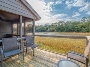 a screened porch with chairs and a view of a river at 1248 Creekwatch Villa in Seabrook Island