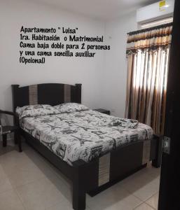 1 cama en una habitación con un cartel en la pared en Apartamentos LUISA en Coveñas