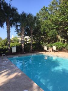 a blue swimming pool with two chairs and palm trees at 2271 Seabrook Island Road in Seabrook Island
