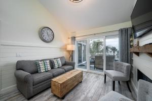 uma sala de estar com um sofá e um relógio na parede em 2940 Atrium Villa em Seabrook Island