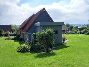 une petite maison bleue sur une pelouse verte dans l'établissement Nouveau - La grange de Saint-Sulpice, à Bellengreville