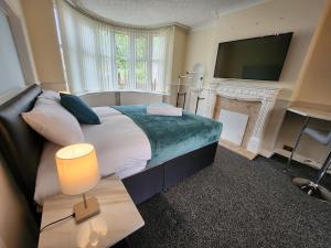 a bedroom with a bed with a fireplace and a television at Sheldon Shared House in Birmingham