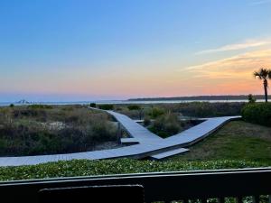 a boardwalk in a field with the sunset in the background at 1391 Pelican Watch Villa in Seabrook Island