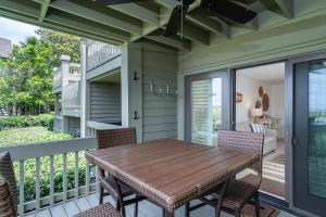 Una terraza con una mesa y sillas de madera. en 1391 Pelican Watch Villa, en Seabrook Island