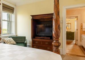 a bedroom with a tv on a wooden entertainment center at Castle Hotel & Spa in Tarrytown