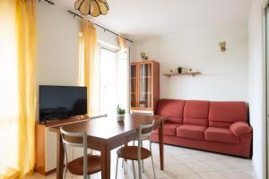 sala de estar con mesa y sofá rojo en Gardappartamenti Costa Pool en Desenzano del Garda