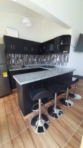 a kitchen with a black counter and bar stools at Apto en Coveñas cerca al mar in Coveñas