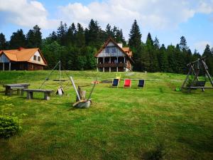 a field with swings and a house in the background at Osada na Granicy - Domki w Bieszczadach in Ustrzyki Dolne