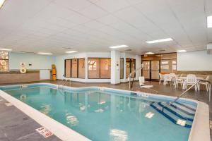 Comfort Inn & Suites Watertown - 1000 Islands في ووترتاون: مسبح كبير في غرفة كبيرة مع طاولات وكراسي