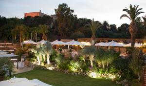 a resort with a garden with umbrellas and palm trees at Hotel Della Valle in Agrigento