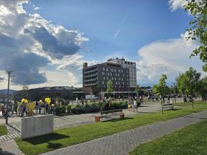 un grupo de personas caminando por un parque con un edificio en Sweet memories Apart Coresi 2, en Brasov