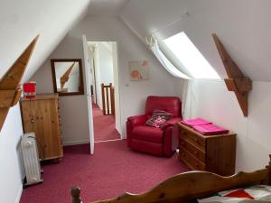 Zimmer im Dachgeschoss mit einem roten Stuhl und einem Fenster in der Unterkunft Rose Cottage in Gorges