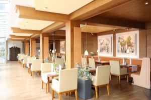 ein Restaurant mit Tischen, Stühlen und Gemälden an den Wänden in der Unterkunft Kurhotel Bad Rodach an der ThermeNatur in Bad Rodach