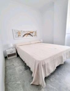 a white bedroom with a bed and a table at Increíble Apartamento Familiar in Mairena del Aljarafe
