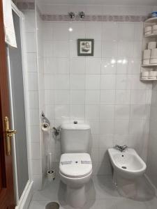 La salle de bains blanche est pourvue de toilettes et d'un lavabo. dans l'établissement Increíble Apartamento Familiar, à Mairena del Aljarafe