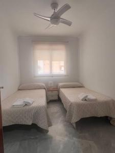Cette chambre comprend deux lits et un ventilateur de plafond. dans l'établissement Increíble Apartamento Familiar, à Mairena del Aljarafe