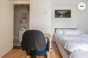 Medway luxury Retreat free parking free wi-fi في تشاتهام: غرفة نوم مع مكتب وكرسي بجوار سرير
