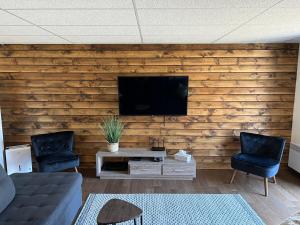 a living room with a wooden wall with a flat screen tv at Vébron 2 in LʼAnse-Saint-Jean