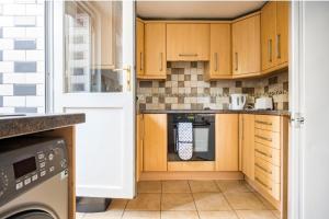 a kitchen with wooden cabinets and a dishwasher at Maidstone castle 3bedroom free sports free parking in Maidstone