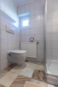 a white bathroom with a toilet and a bath tub at Landhaus MONTANA in Rauris