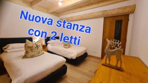 two beds in a room with a sign on the wall at Baita Pra Petina Pale di San Martino in Siror