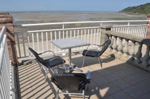 una mesa y sillas en un balcón con vistas al océano en Villa les Dunes, en Saint-Jean-le-Thomas