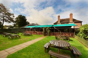 un grupo de mesas de picnic en un patio con un edificio en Camden Arms Hotel en Royal Tunbridge Wells