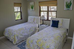 a bedroom with two beds and two windows at Water Mills- Beach Apartments in Mammee Bay