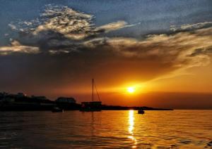 a sunset over a body of water with a boat at CASA DIVINO in Bari