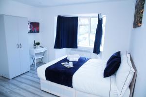 a bedroom with a bed with a blue blanket and a window at Lovely Apartment with free parking on premises. in London