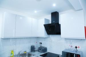 a kitchen with white cabinets and a sink at Lovely Apartment with free parking on premises. in London