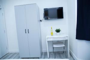 a white desk with a chair and a tv on a wall at Lovely Apartment with free parking on premises. in London