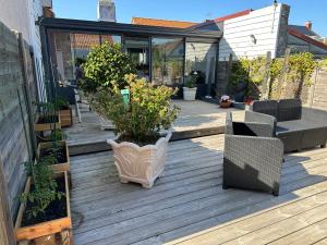 een patio met stoelen en planten op een houten terras bij Villa les Buissonets in Berck-sur-Mer