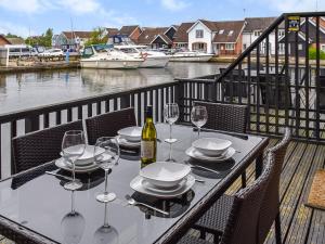 a table with plates and wine glasses on a balcony at Lilys Cottage in Wroxham