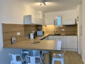 a kitchen with white cabinets and a wooden counter top at LA BADINE Appartement 5 personnes avec balnéo et clim in Hyères