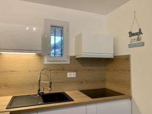 a kitchen with a sink and white cabinets at LA BADINE Appartement 5 personnes avec balnéo et clim in Hyères