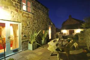 a stone building with a patio at night at Heather Cottage in Kirk Ireton