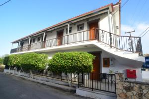une maison blanche avec un balcon et des buissons dans l'établissement Periyali Studios, à Laganas