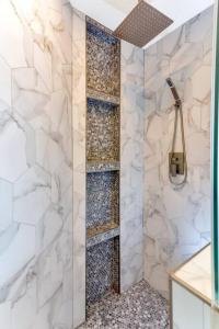 a bathroom with a shower with white marble walls at The Oasis at West U Top-Floor Heated Pool & Spa in Houston